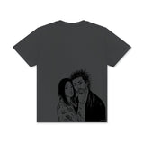 A black t-shirt featuring a graphic print of two characters, a man and a woman, in a casual, relaxed pose.